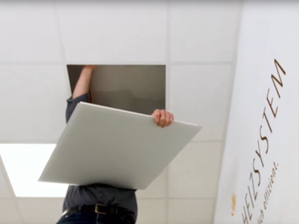 Das Bild zeigt einen Installateur der eine Vitramo Infrarotheizung VH06262 in eine Systemdecke einlegt.